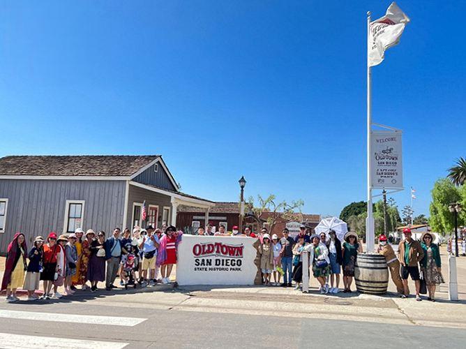 A group of people standing in front of a flag poleDescription automatically generated