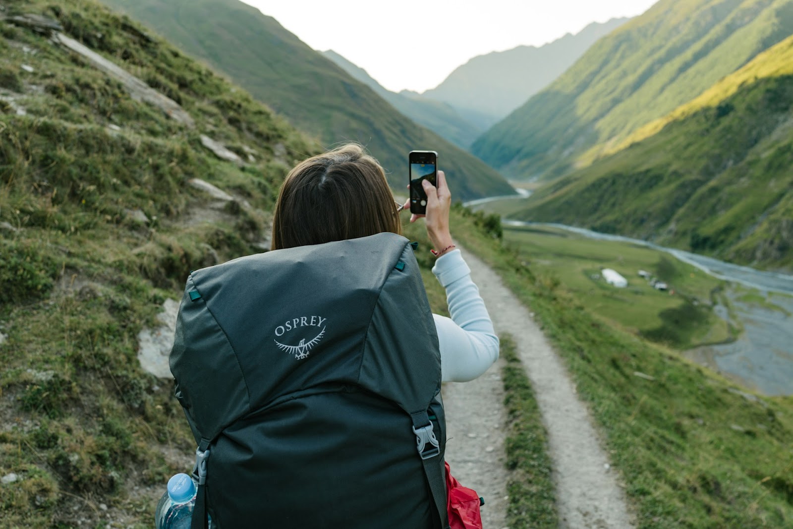 Woman holds a mobile device that's on her Backpacking Checklist.