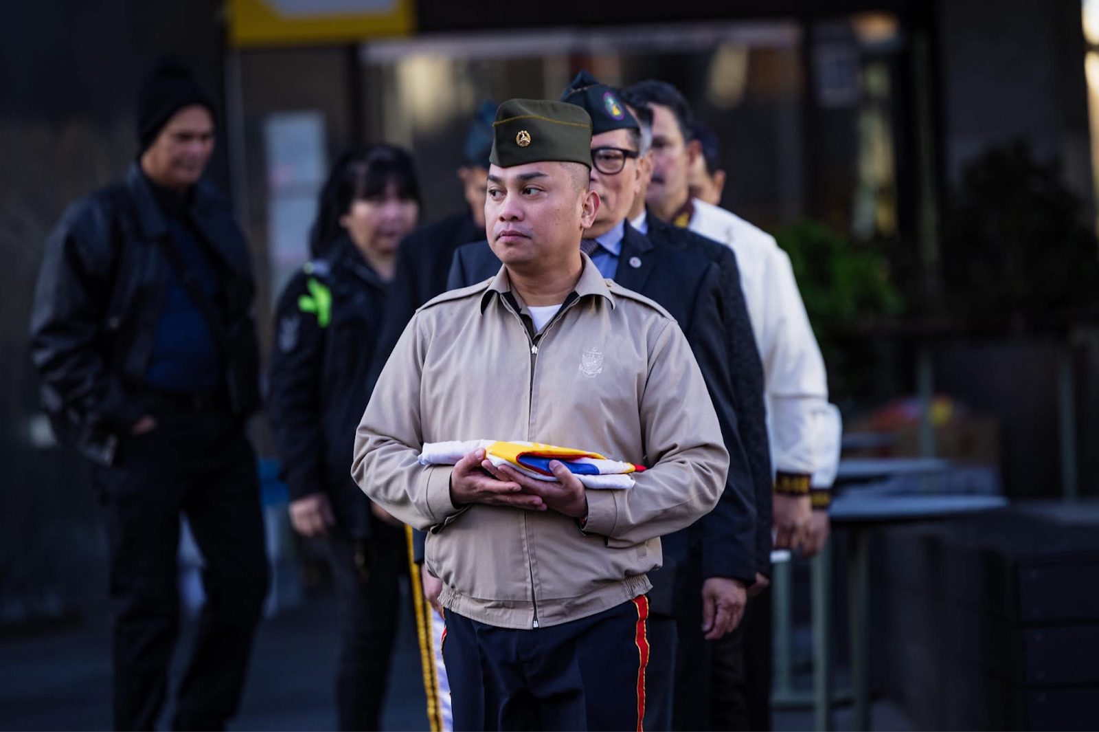 A person in a military uniform holding booksDescription automatically generated