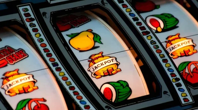 Close-up of a slot machine with bright, colorful symbols, including fruits and the word 'JACKPOT' displayed on the reels.