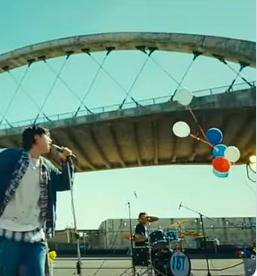 This contains an image of BTS Jin singing and seven ballons in the air and a drummer 