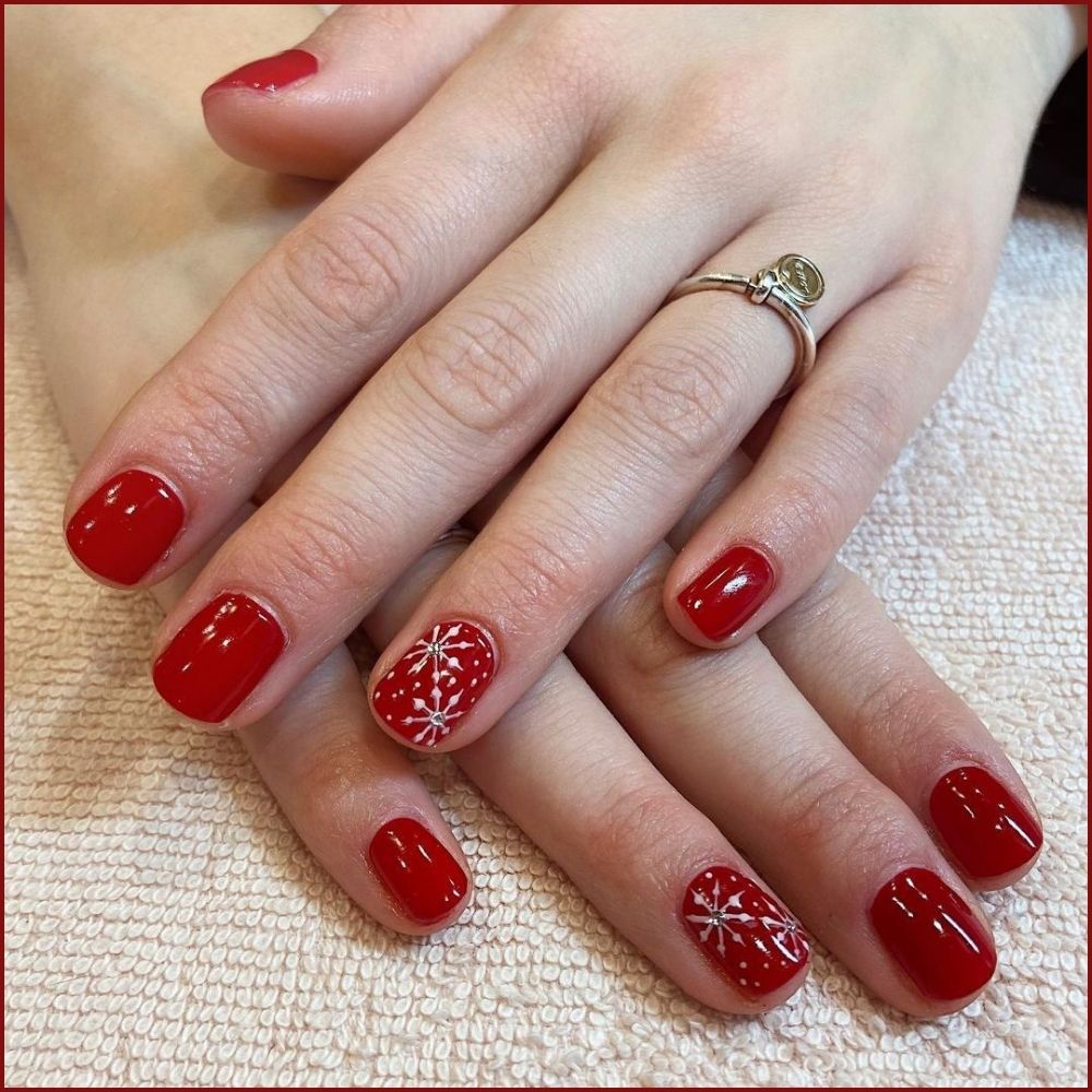 Close up of hands having Christmas red nails with Snowflake-Inspired Red Designs