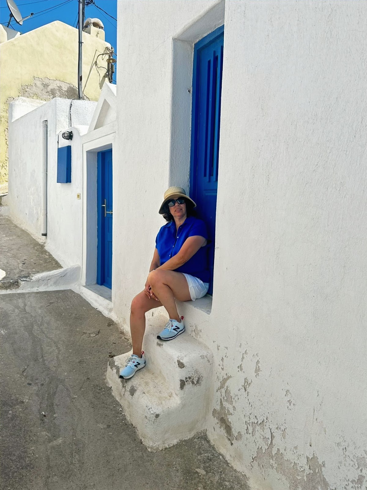 Santorini’s Caldera and Whitewashed Villages, woman sitting on stoop