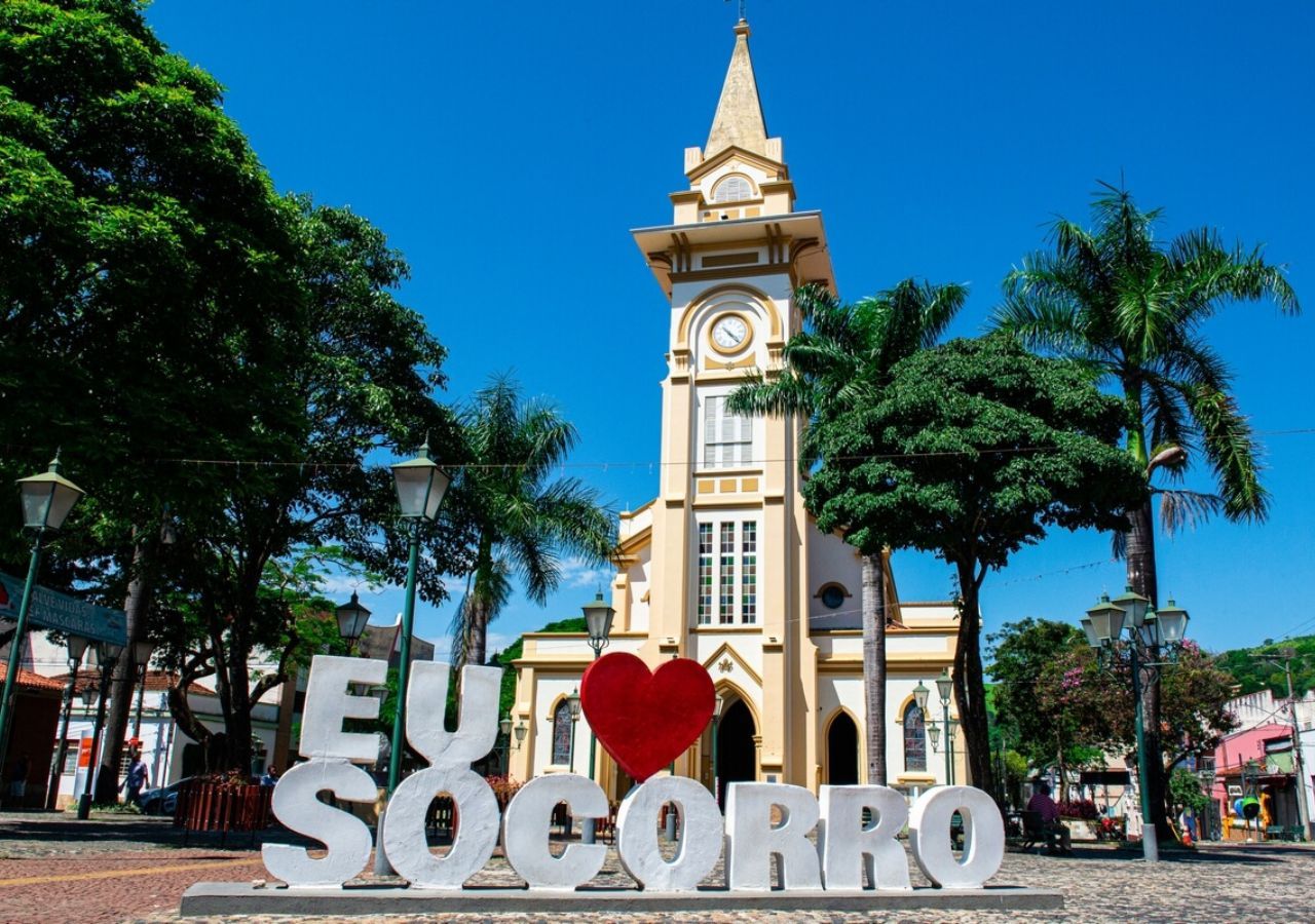 Igreja Nossa Senhora do Perpetuo Socorro em Socorro SP, com árvores e calçadão ao redor.