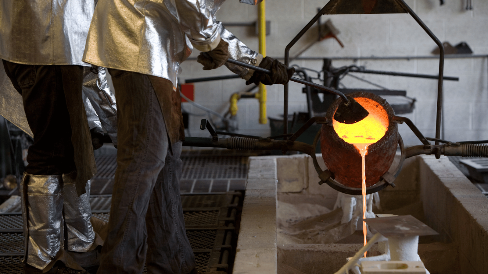 Pouring molten metal into a ceramic mold during the investment casting process.