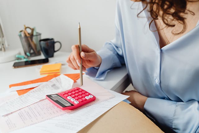 person calculating property expenses on pink calculator