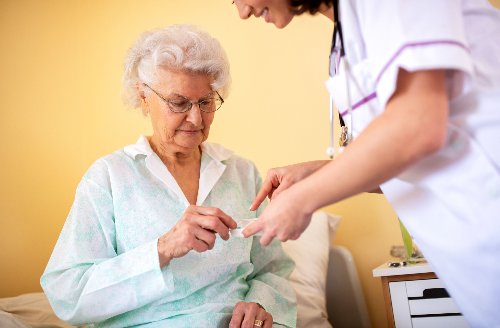 A skilled nurse hands a senior their medications for the day.