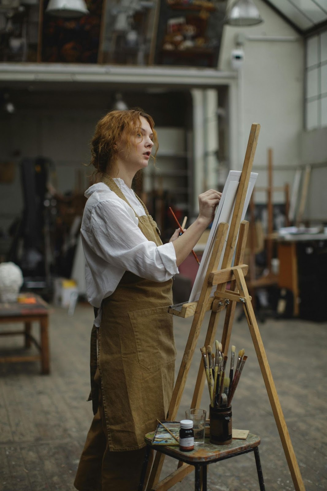  A girl standing and drawing faceless portrait  on a canvas with focus and creativity.