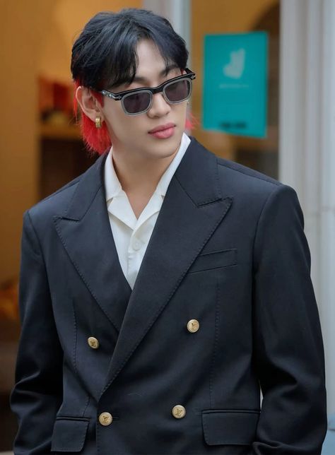 This contains an image of GOT7 BamBam with black hair wearing sunglasses and a blazer jacket, standing in front of a building