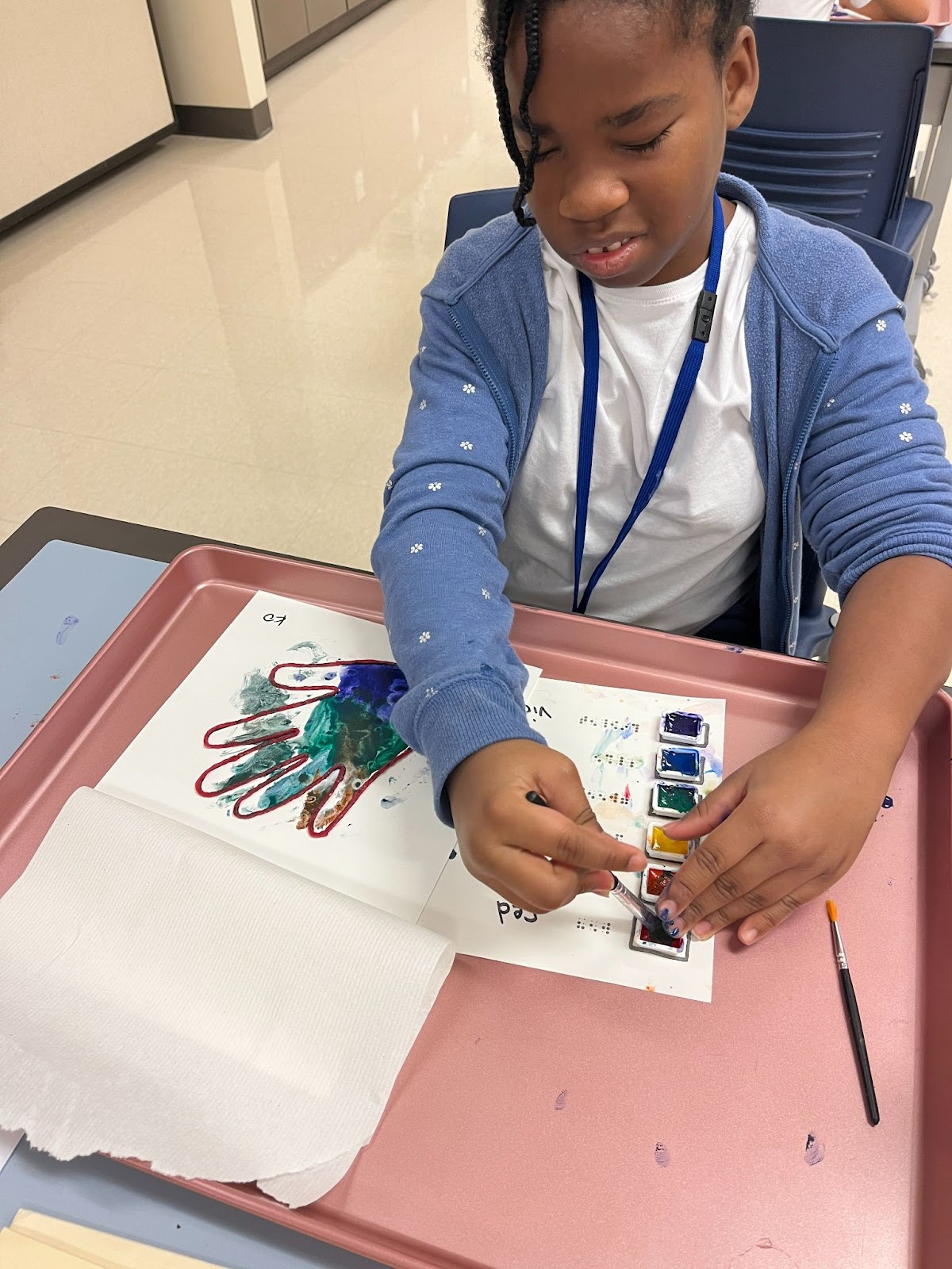 Student painting tactile hand with watercolors