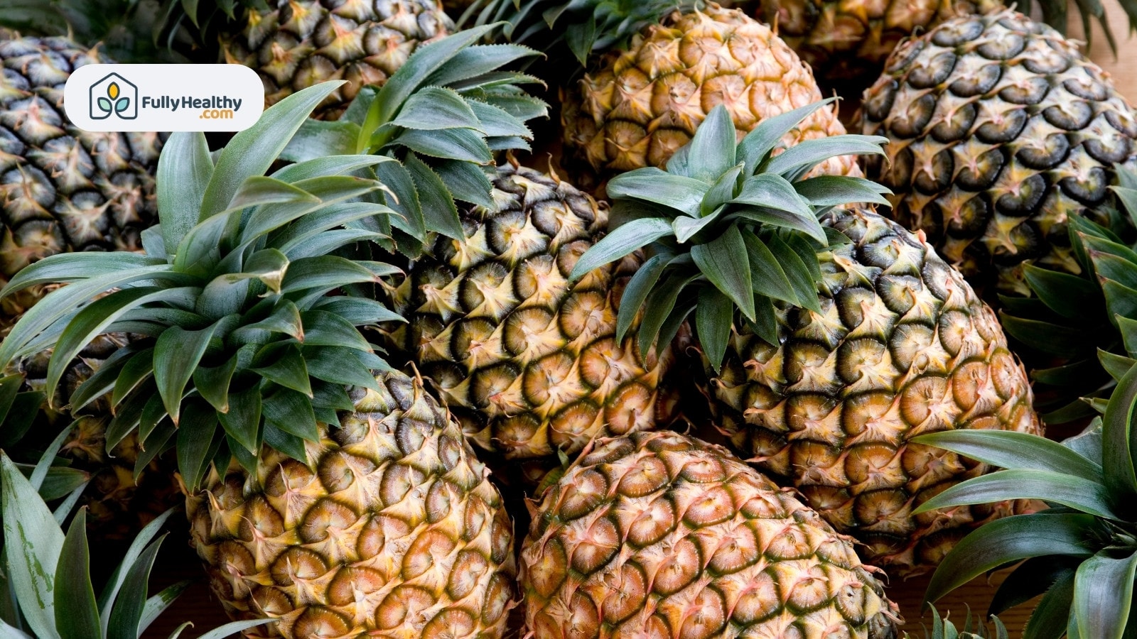 Large ripe pineapples with green tops in a market pile