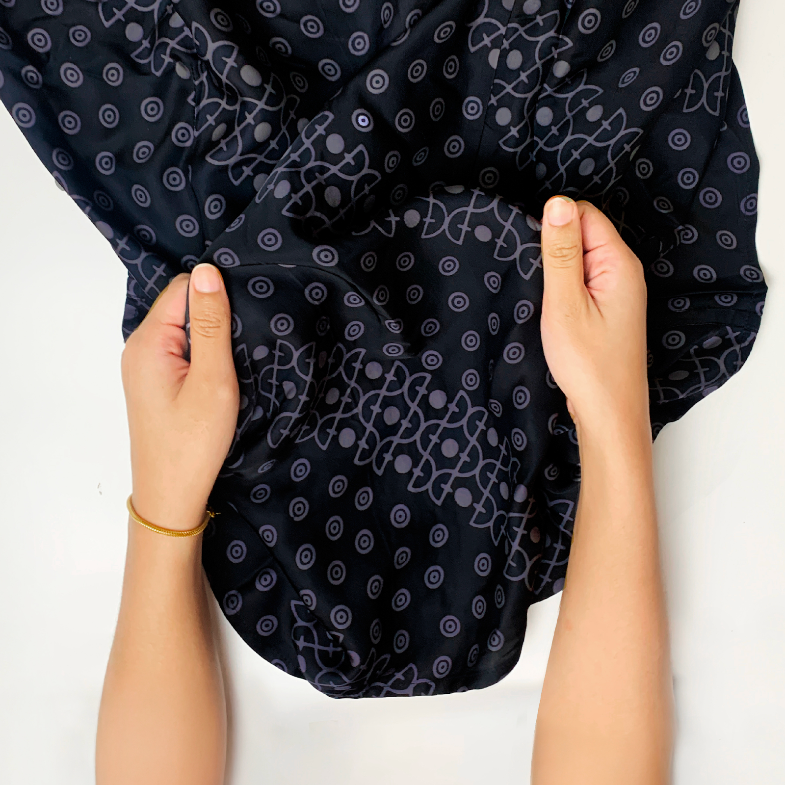 An image showing women hand is holding Jet Alur long sleeved men shirt fabric