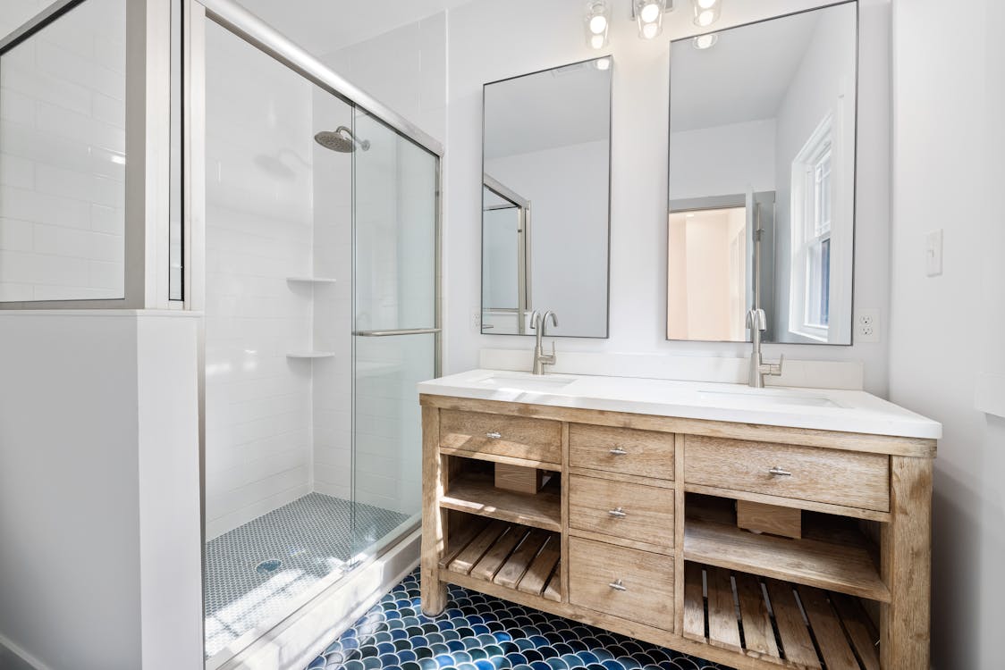 Free Bright and airy bathroom featuring dual mirrors and a wooden vanity with modern fixtures