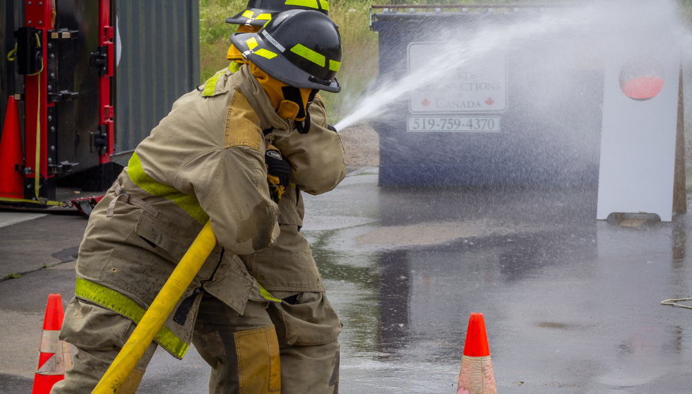 A firefighter spraying water on a fire hydrant

Description automatically generated