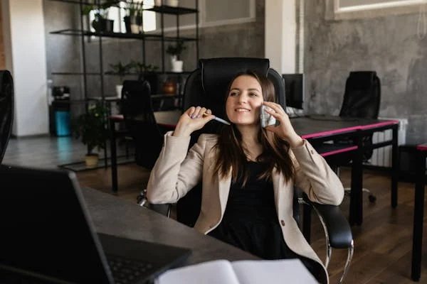 Photo of a female manager smiling while talking on the phone in an office, demonstrating communication skills for managers