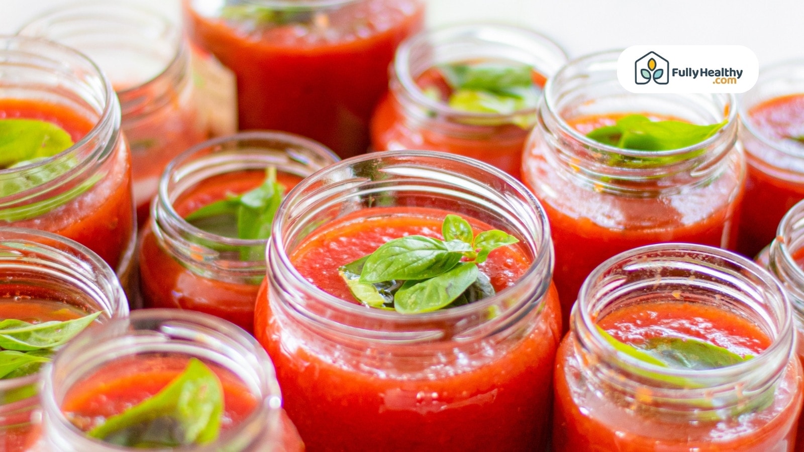 Jars of fresh tomato sauce topped with basil leaves