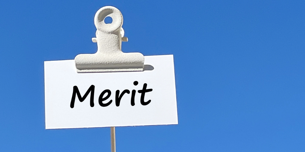 快晴の青空を背景に、木製クリップで留めた白いカードに手書き風の黒文字で「Merit」と書かれたシンプルなメリット提示画像