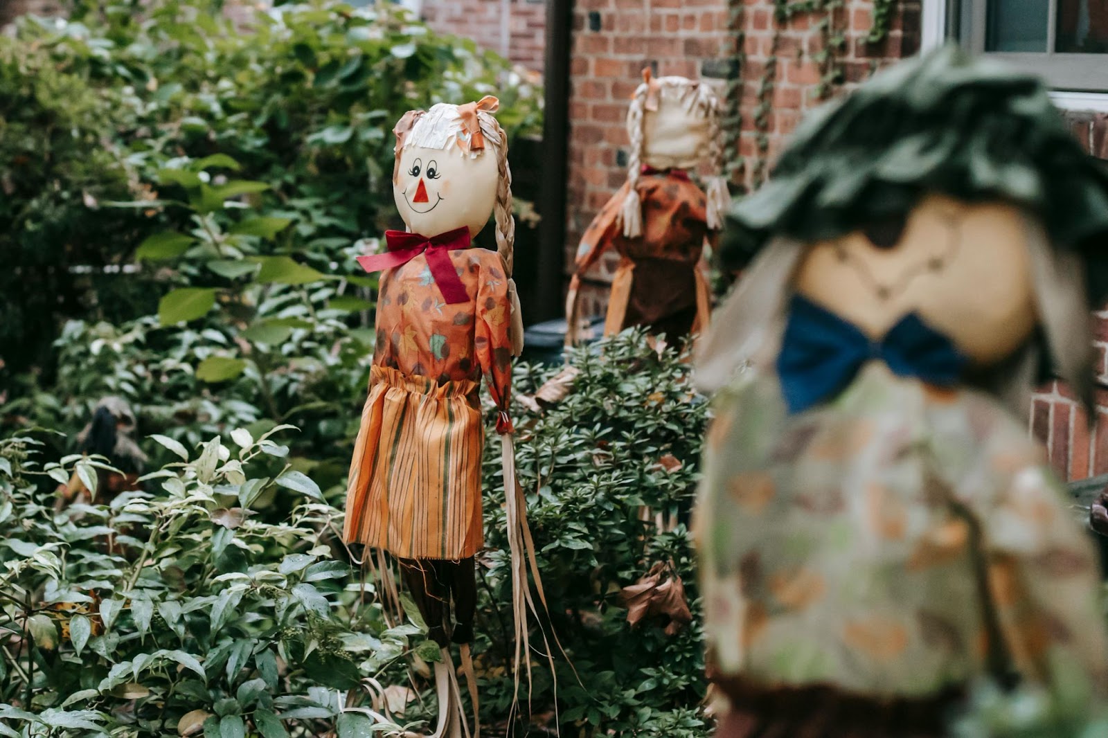 A garden with three smiling scarecrows