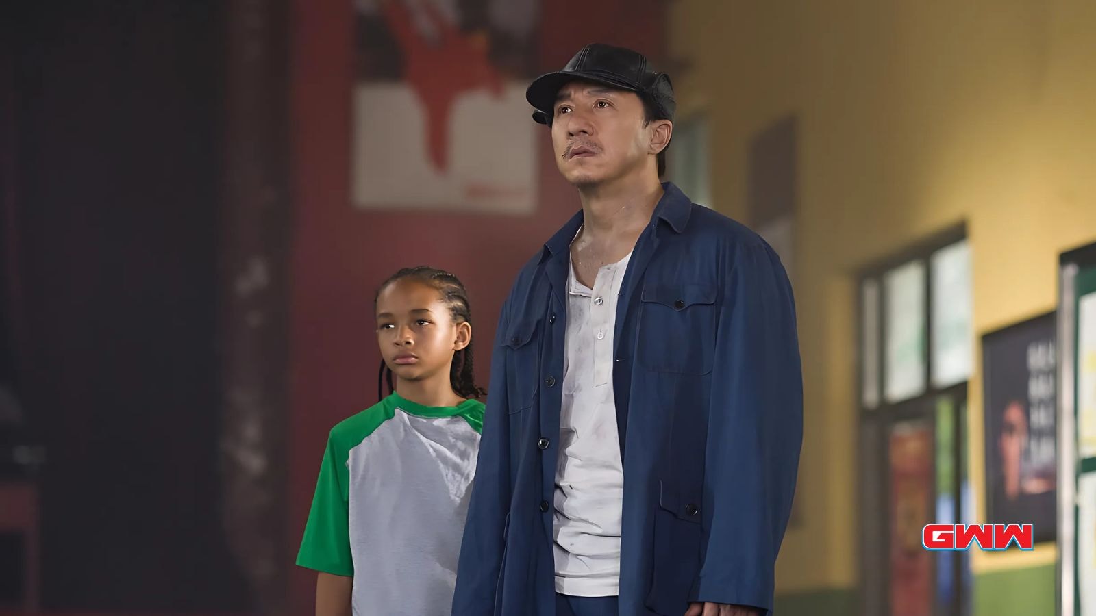 Jackie Chan and Jaden Smith observing inside a martial arts studio.