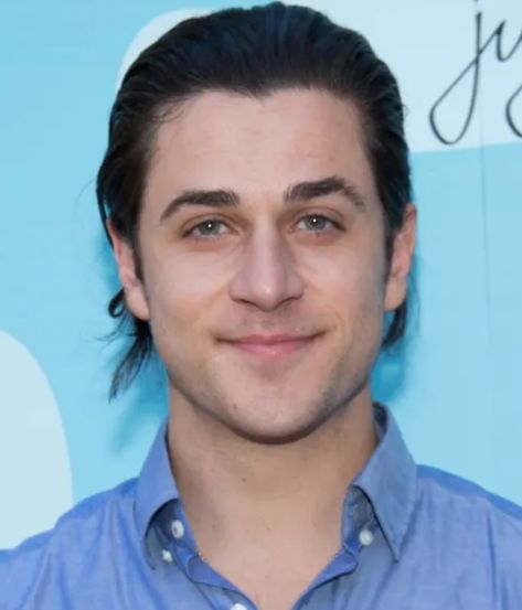 This contain David Henrie wearing a blue shirt and looking at the camera with a smile on his face