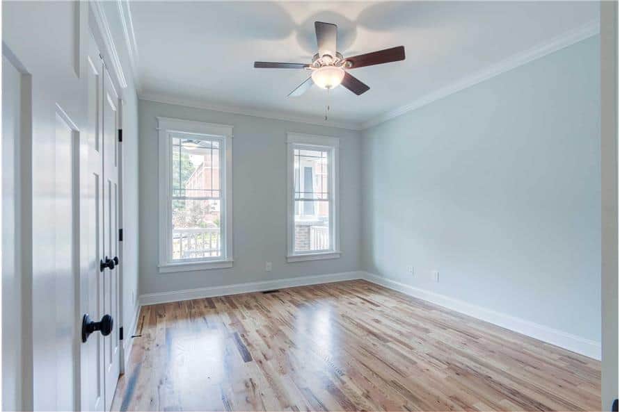 Third bedroom with white hardwood flooring, framed windows, and light gray walls lined with white moldings.