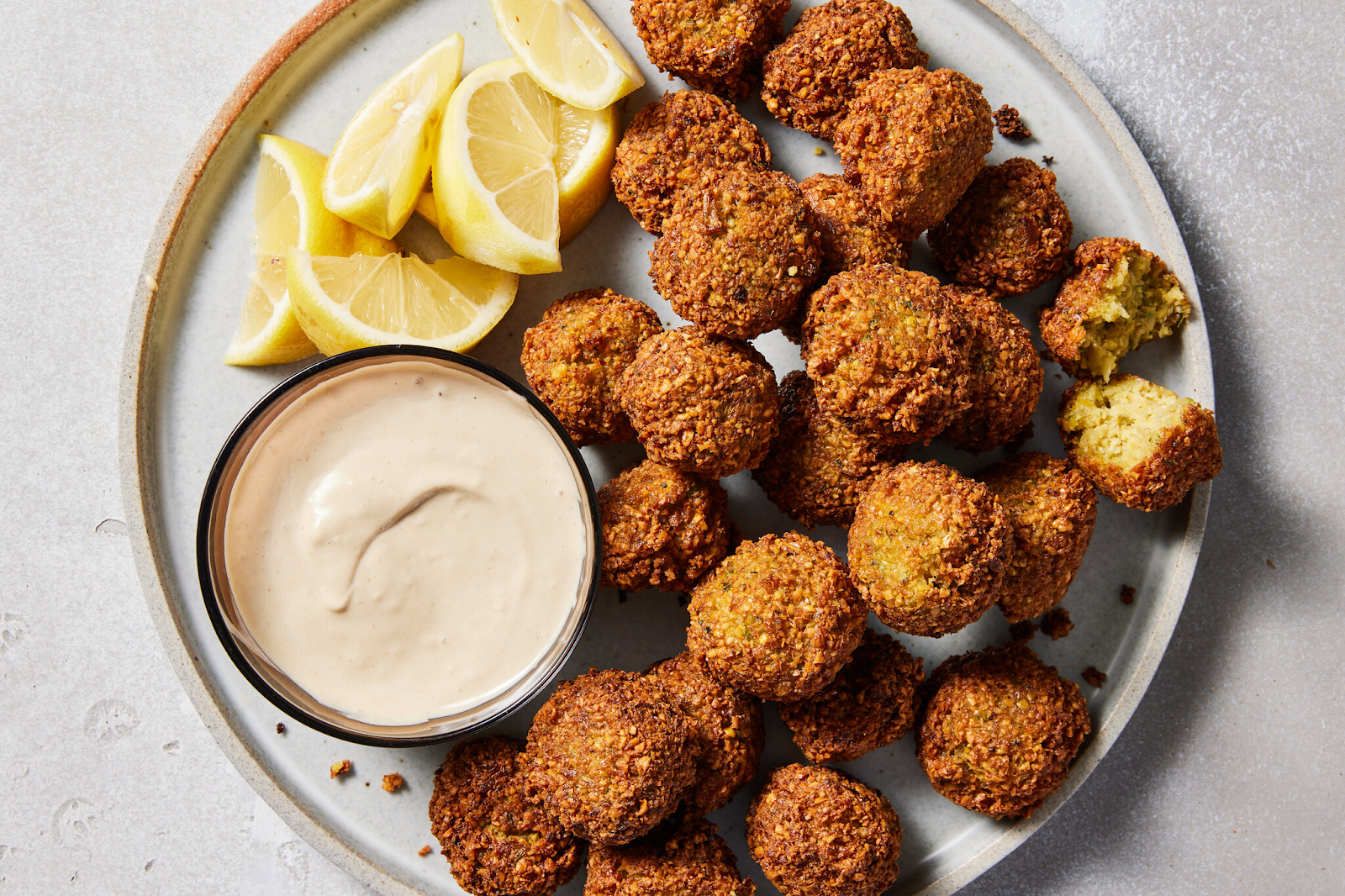 Crispy golden brown falafel, the best local street food, on a plate served with lemons and dip - (Credits The New York Times)
