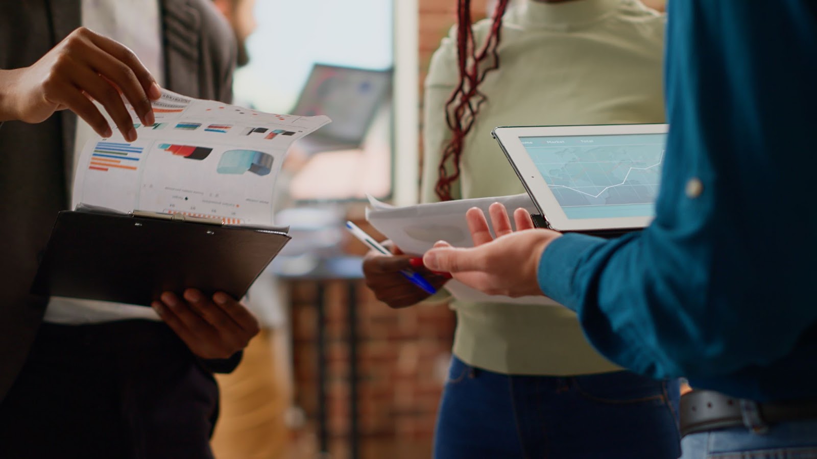 People using tablets and looking at data on clipboards. 