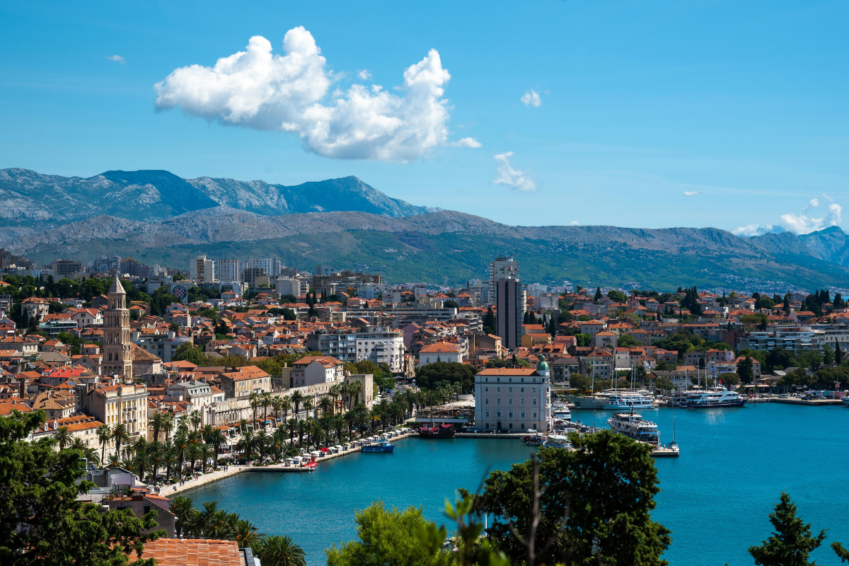 Clean and clear water and group of houses near the sea and tall mountains are there
