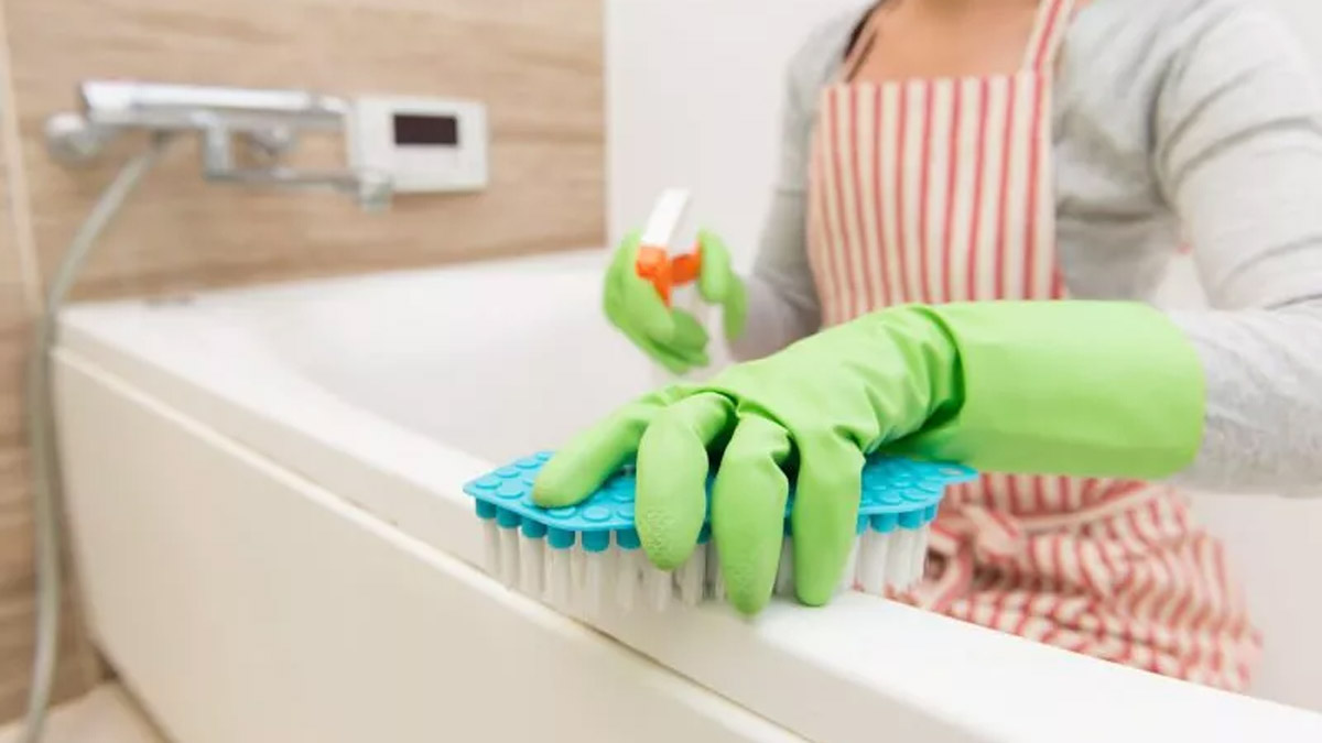 A woman is cleaning with the brush and shower