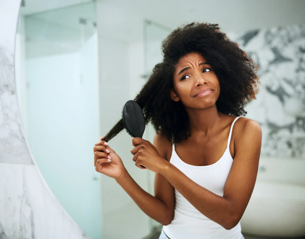 Curly hair being combed with dull, rough ends—split ends curly hair often appears dry and lacks shine.