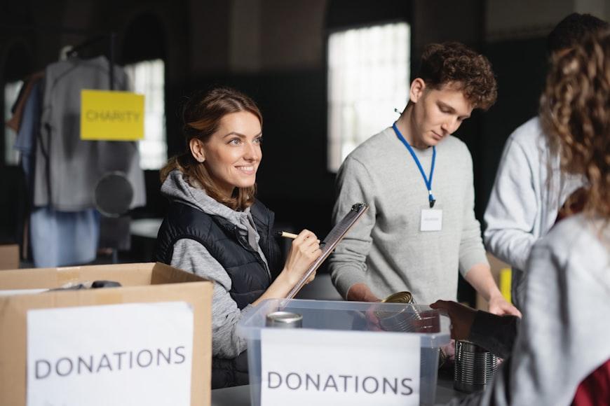 A group of volunteers working in a community charity donation Centre, sorting clothes and canned food.