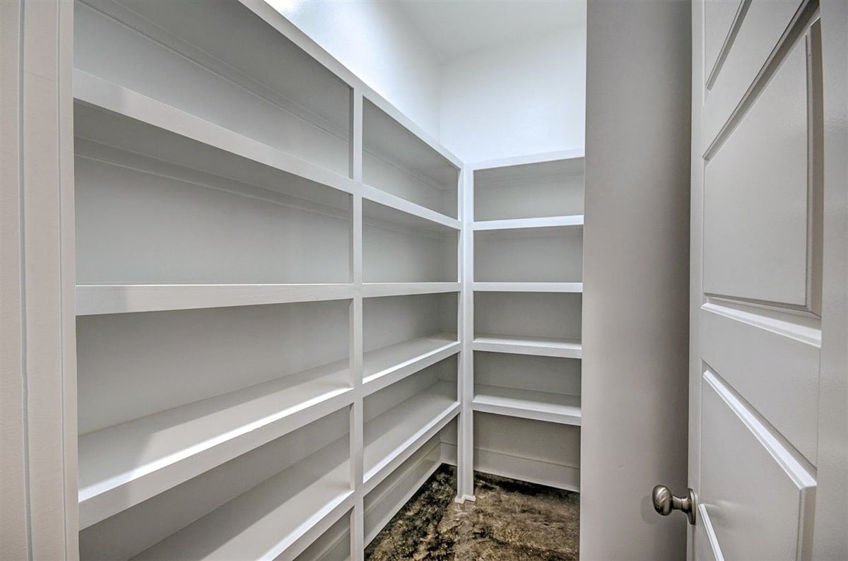 The walk-in pantry is filled with white built-in shelves.