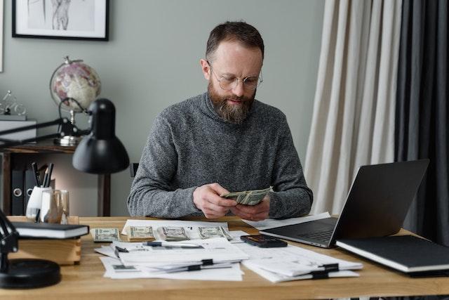  A man in a gray long sleeves shirt counting money.