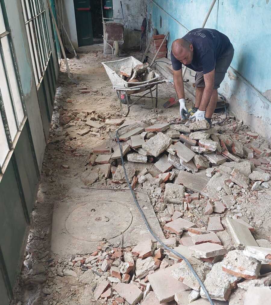 A man bending over around the rubble of the Limonaia mid-demolition.