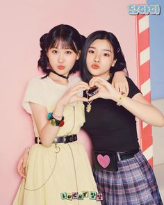 This may containLucky Vicky members standing next to each other in front of a pink wall holding up their hands