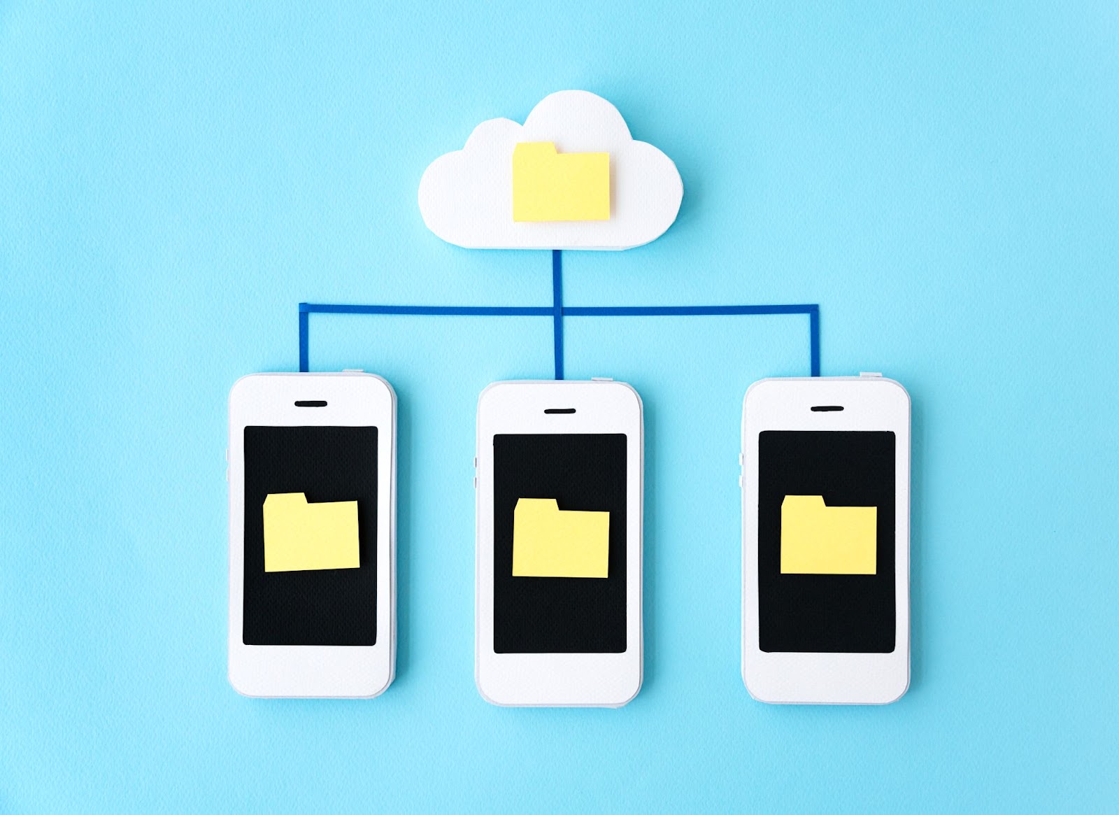 Three mobile devices displaying folders on their screens, interconnected to a cloud with a folder using blue tape lines against a blue background.