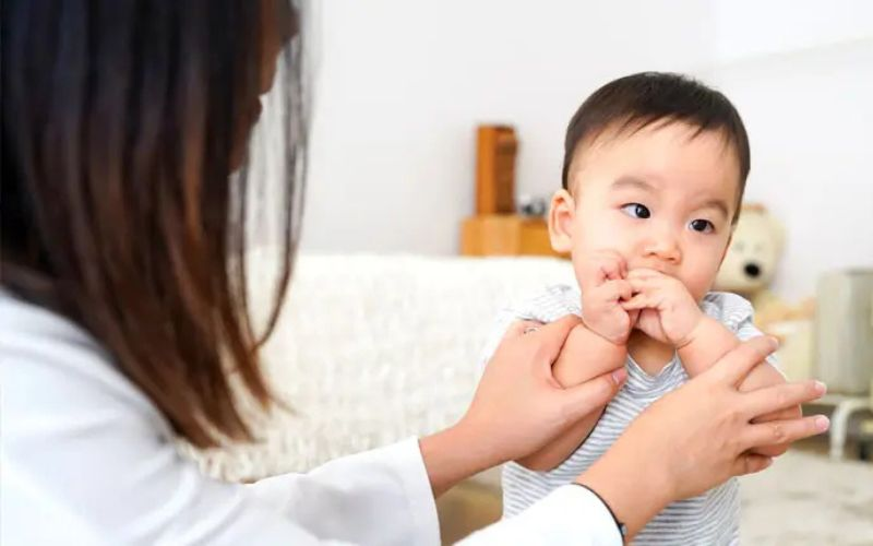Adult  supporting a baby.