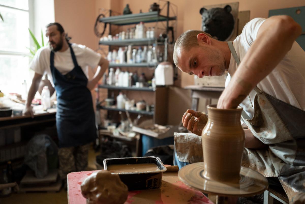 A man shapes a clay vase on a pottery wheel