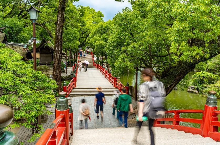 A group of people walking down a red bridgeDescription automatically generated