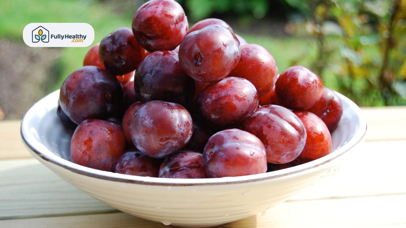White bowl filled with freshly washed juicy red plums