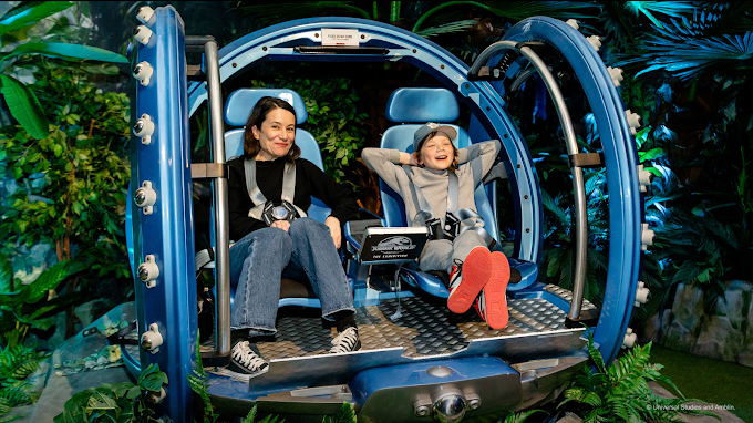 Visitors sitting in the cradle at Jurassic World: The Exhibition, interacting with life-sized dinosaur displays at The Trafford Centre, Manchester