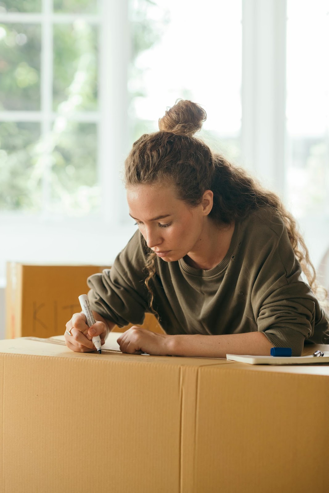 A woman writing on a moving box | Source: Pexels