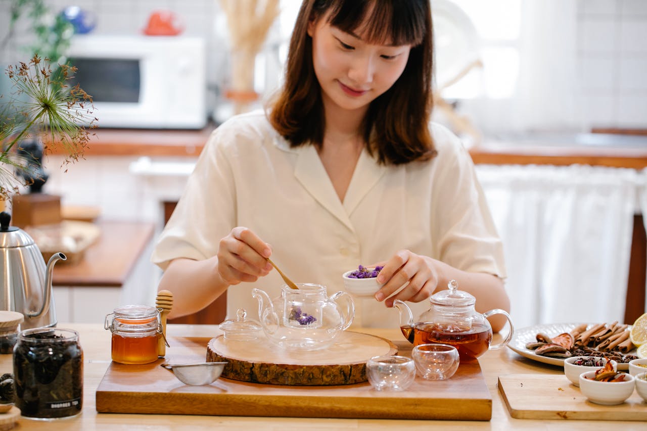 A woman in a white shirt is preparing tea in a cozy kitchen. 