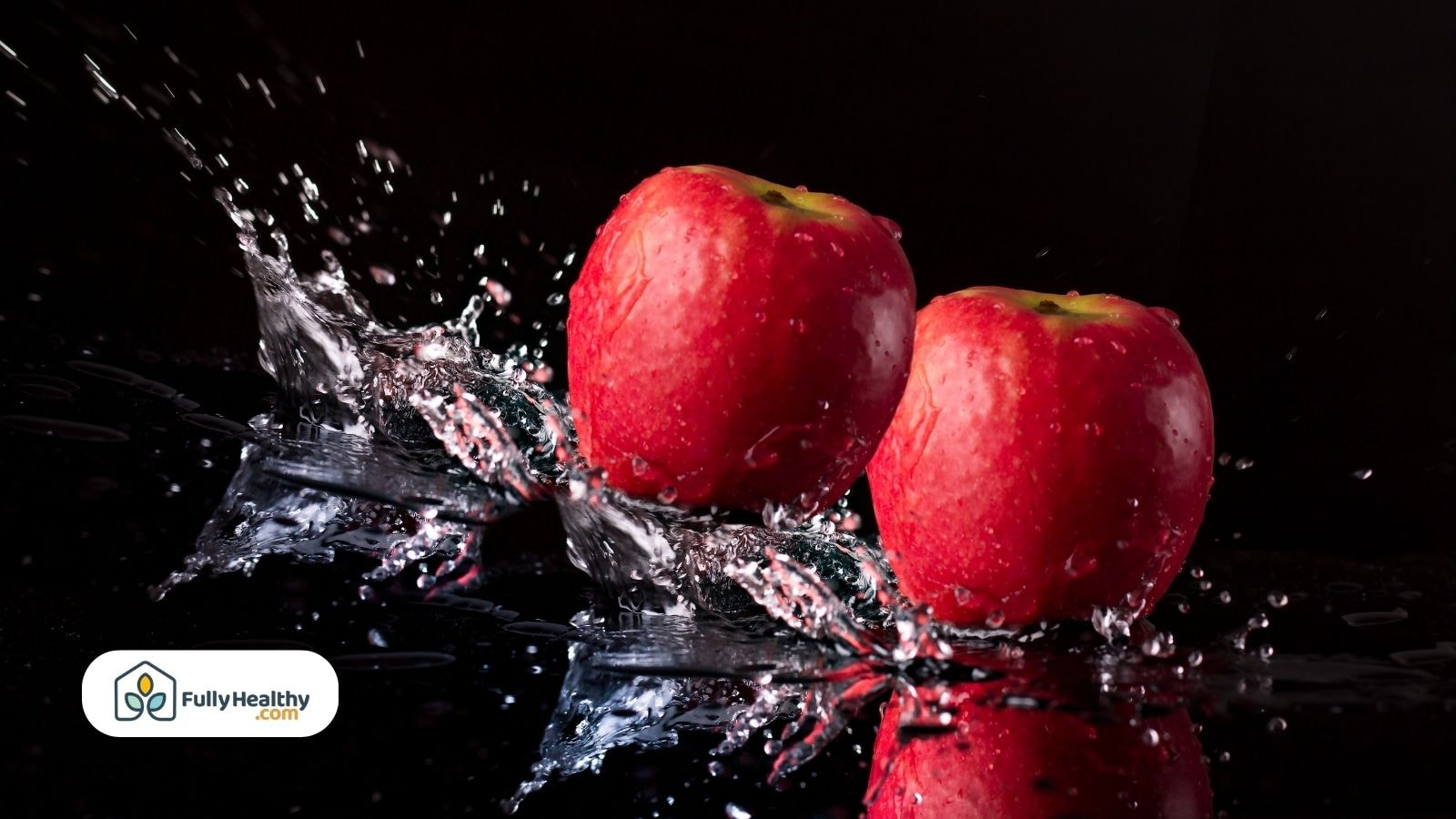Red apples splashing in water against black background setting