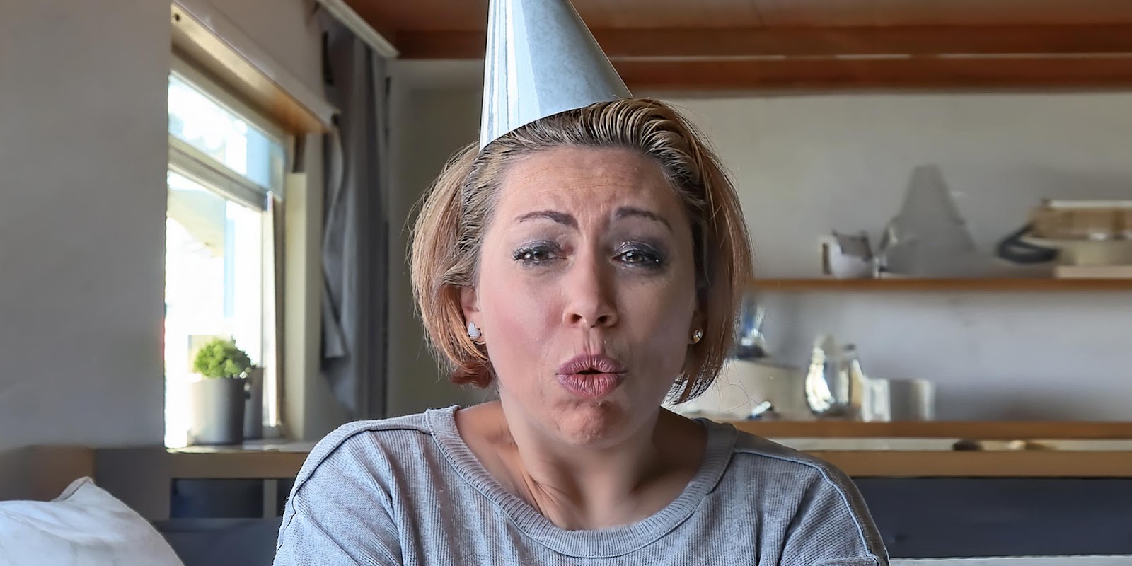 A shocked woman wearing a party hat | Source: Midjourney