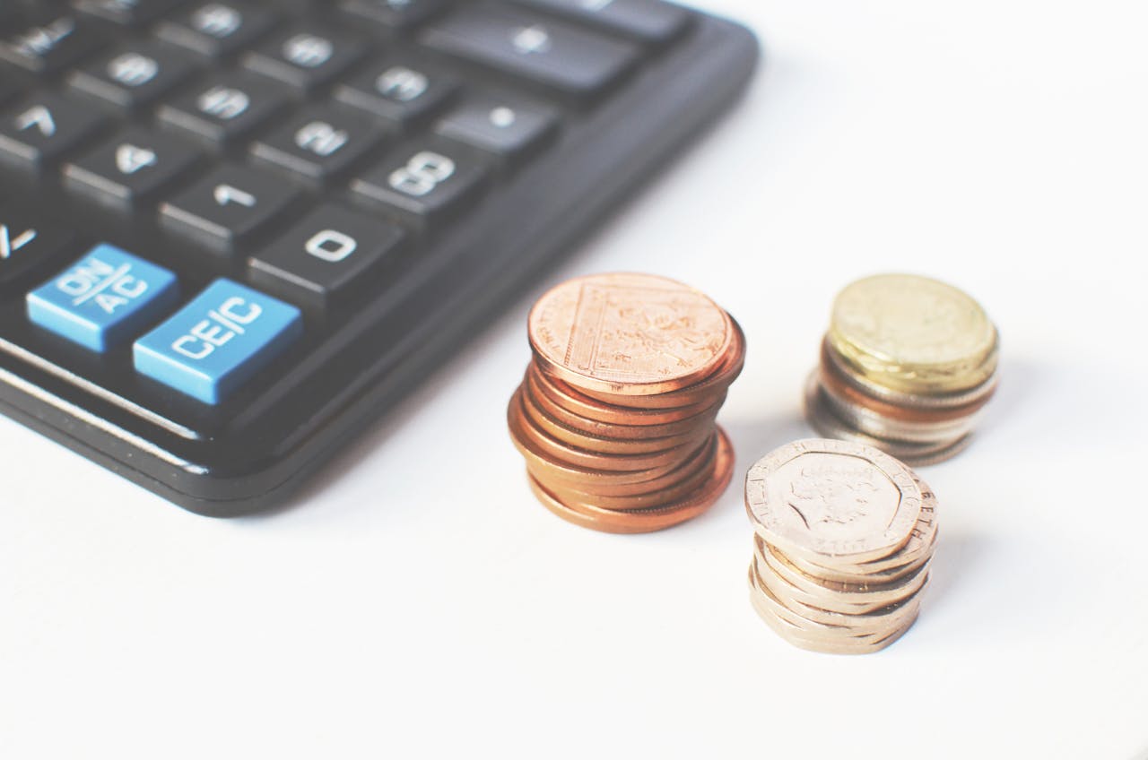 Close-up of a calculator with stacks of coins next to it, symbolizing financial management and budgeting.