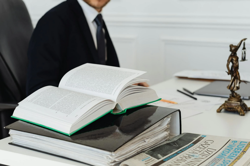 A person in a suit and tie sitting at a desk with a stack of books