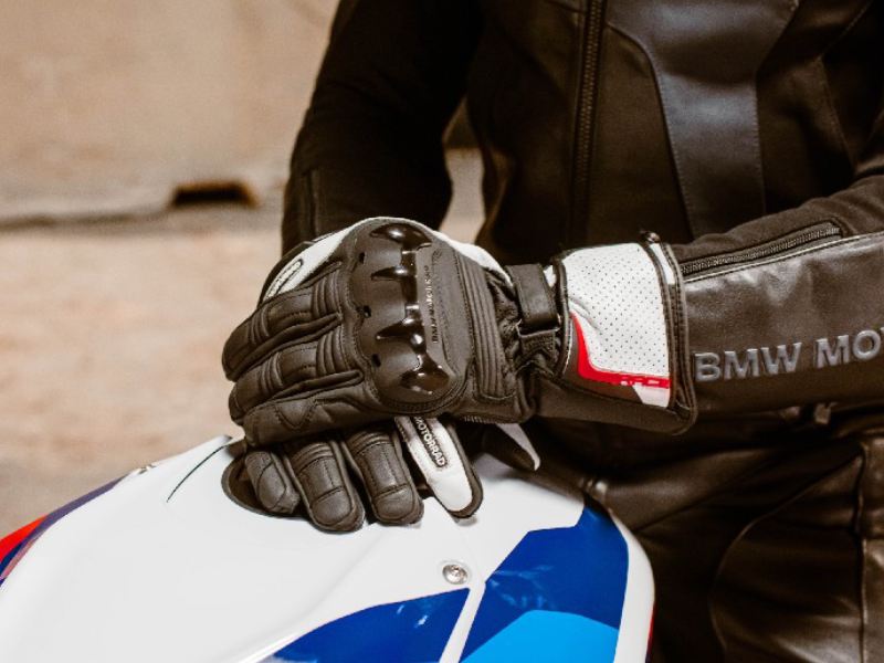 a motorcyclist sitting on a BMW motorcycle with a close-up on his BMW Pro Race gloves