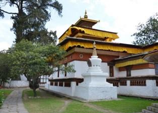 A white building with a yellow roof with Kinkaku-ji in the backgroundDescription automatically generated