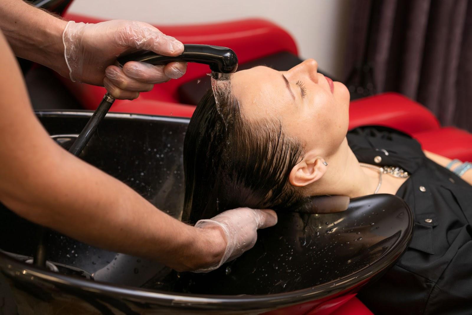 Hairdresser washing woman’s hair